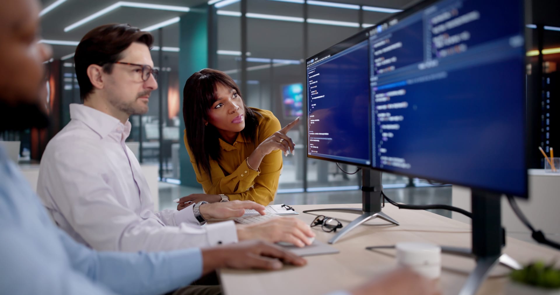 Three colleagues collaborating on a code review in a modern office