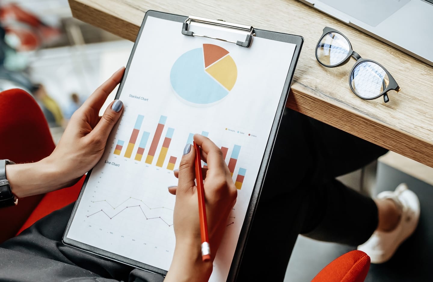 Person holding a clipboard with business charts and graphs.