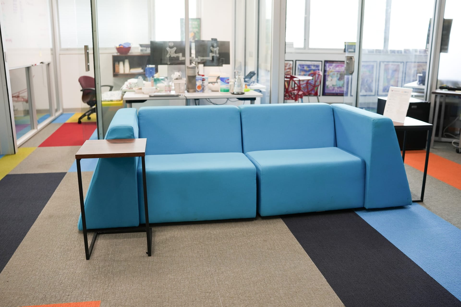 Modern office lounge area with blue couch and collaborative workspace