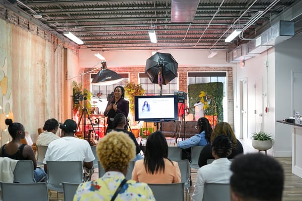 A speaker addresses an audience in a modern, well-lit venue.