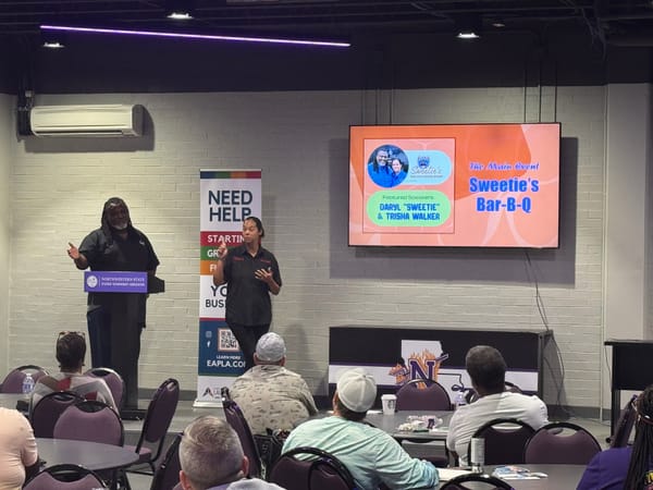 Two presenters speaking on stage at a Sweetie's Bar-B-Q event.