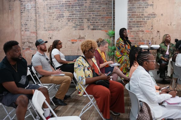 A group of people seated in a room with exposed brick walls attending a seminar.