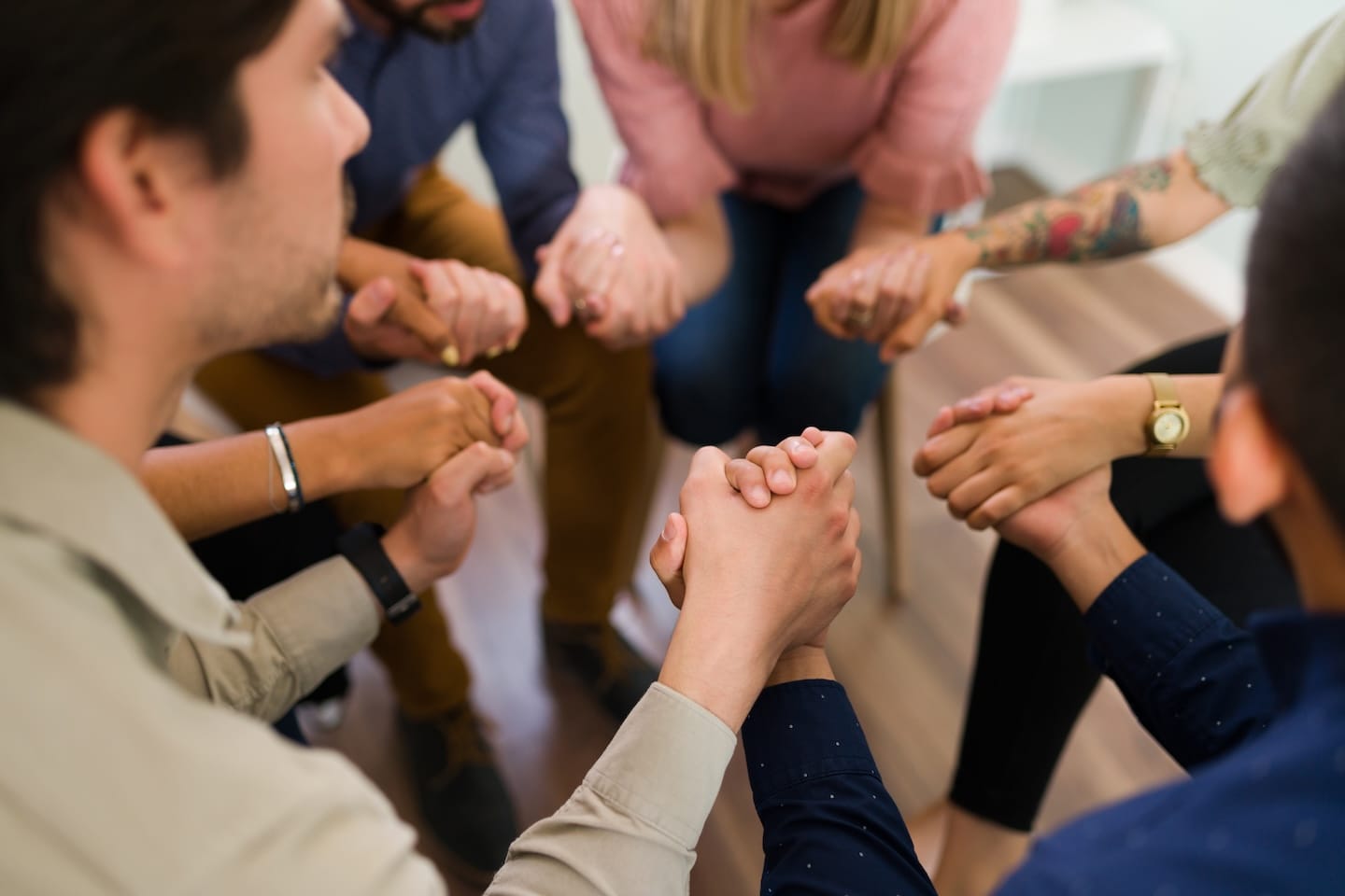 A group of people sitting in a circle holding hands.